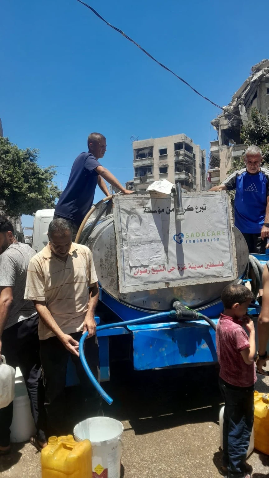 Distribution d’eau aux familles depuis une citerne portant le logo SADACARE