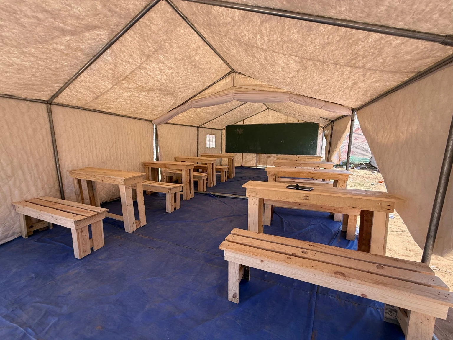 Un nouvel espace de classe sous tente, équipé de tables, bancs et tableau