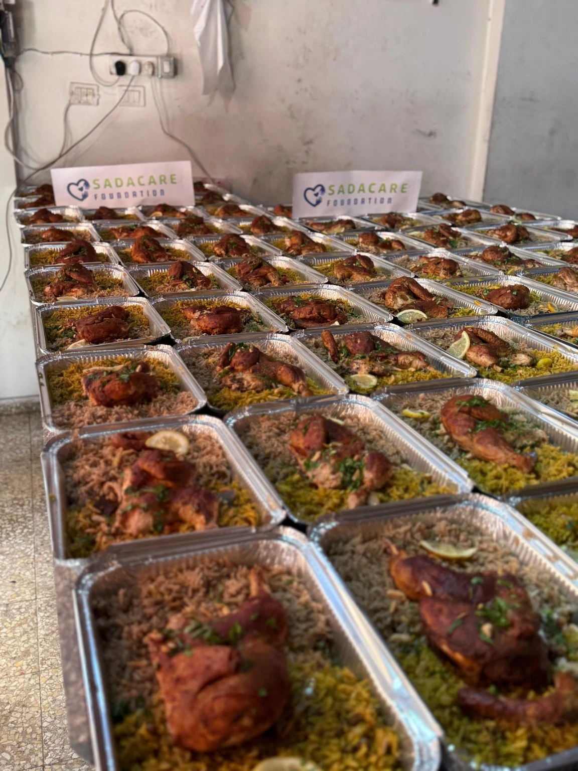 Des barquettes de repas préparées pour la distribution, avec des panneaux SADACARE